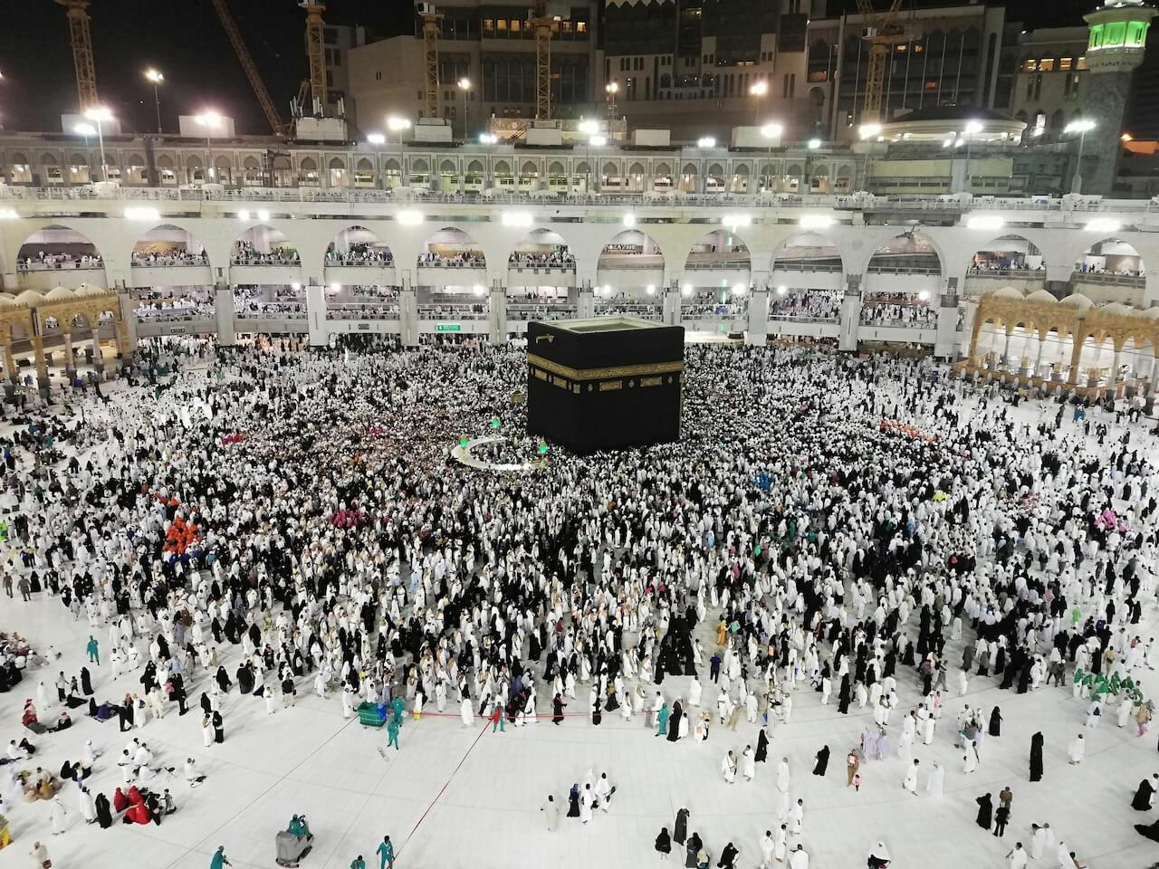 Large crowd gathered around the Kaaba in Mecca at night.